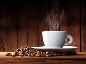 Cup of coffee with coffee beans on a beautiful brown background.
