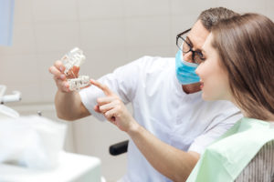 Man dentist show dentures teeth at dental surgery to his patient