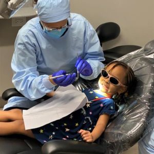 A dentist providing pediatric dentistry care for a child.